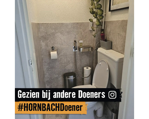 Modern toilet met wandtegels in steenlook, wit toilet, bidetdouche, afvalbak en toiletrolhouder van roestvrij staal.