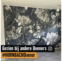 Fotobehang met groot bloemenpatroon op een wand in een lichte kamer met houten vloer en Instagram Logo.