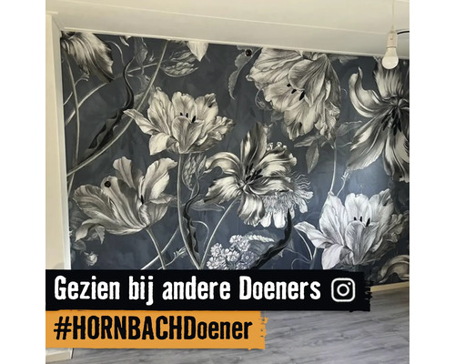 Fotobehang met groot bloemenpatroon op een wand in een lichte kamer met houten vloer en Instagram Logo.
