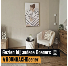 Moderne zithoek met een witte bouclé fauteuil, een spiraalvormige bijzettafel, houten dressoir en een groot schilderij aan een beige muur.