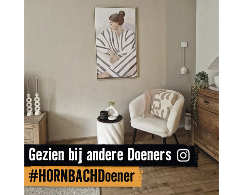 Moderne zithoek met een witte bouclé fauteuil, een spiraalvormige bijzettafel, houten dressoir en een groot schilderij aan een beige muur.