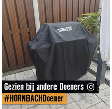 Tenneker barbecuehoes met Tenneker Logo op een barbecue op een terras met houten schutting.