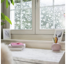 Raamfolie met bloemen- en rankenpatroon in wit op een matte ondergrond, decoratieve privacyfolie in een lichte kamer.