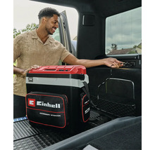 Draagbare Einhell koelbox met opbergvak, aangesloten op een 12-volt aansluiting in de kofferbak van een auto.