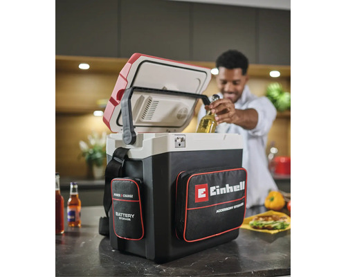 Einhell Power X-Change accu koelbox met opbergvakken in een keuken, een man haalt een flesje drinken uit de geopende koelbox.
