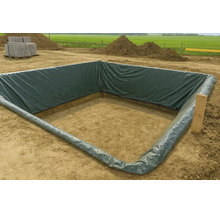 Een vierkante bouwput bekleed met een donkergroene PE-folie op een bouwplaats met hopen aarde op de achtergrond.