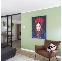 Woonkamer met groene muur, ingelijst schilderij van een vrouw, bruine lederen fauteuil en zwarte glazen deur naar de aangrenzende kamer.