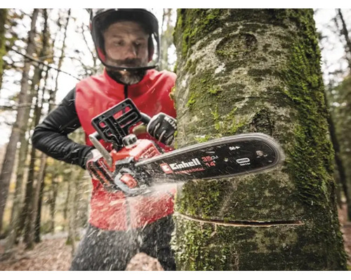 Persoon zaagt een boomstam in het bos met een Einhell accu-kettingzaag, zwaardlengte 35 centimeter.