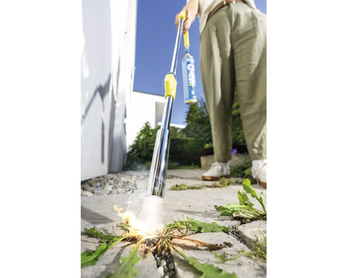 Persoon gebruikt een gas onkruidbrander voor thermische onkruidbestrijding op een bestrate oppervlakte buiten.