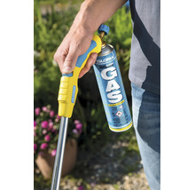 Een persoon houdt een Gloria Thermoflamm gasbrander met gascartouche vast in de tuin voor onkruidbestrijding.