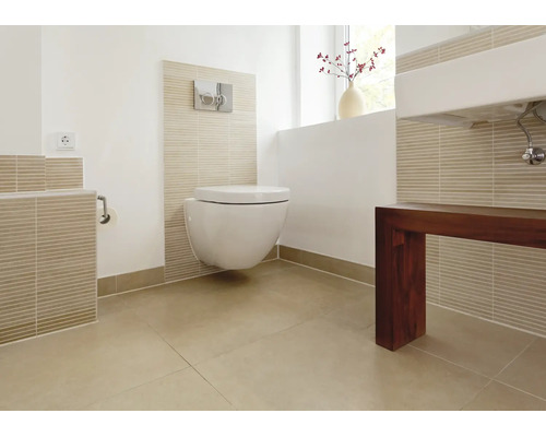 Moderne badkamer met hangend toilet, voorzetwand, tegels in natuurlijke tinten en een wastafel met donkerhouten onderkast.