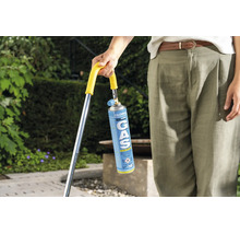 Persoon houdt Gloria gascartouche voor een onkruidbrander vast in de tuin