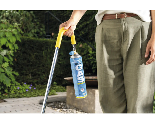Persoon houdt Gloria gascartouche voor een onkruidbrander vast in de tuin