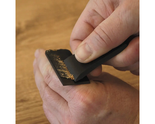 Een persoon gebruikt een speciale handschaaf voor het handmatig bewerken en verwijderen van houtoppervlakken.