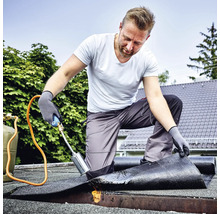 Vakman die bitumen dakbedekking vastbrandt met een gasbrander op een plat dak.