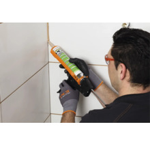 Een vakman brengt met een kitpistool PCI Silicofug kit aan in de tegelvoeg.