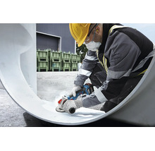 Vakman met beschermende kleding gebruikt een Bosch accu haakse slijper voor het bewerken van een groot werkstuk op een bouwplaats.