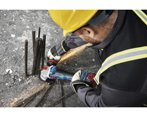 Een bouwvakker met veiligheidshelm slijpt metalen staven op een bouwplaats met een accu haakse slijper van Bosch Professional.
