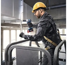 Vakman met veiligheidshelm en harnas gebruikt een Bosch accu slagschroevendraaier voor het monteren van metalen ventilatiekanalen op een hoogwerker.