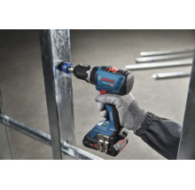 Een accu boorschroefmachine van Bosch Professional boort met een gatenzaag in een metalen profiel voor gipsplaten.