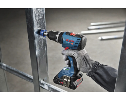 Een accu boorschroefmachine van Bosch Professional boort met een gatenzaag in een metalen profiel voor gipsplaten.