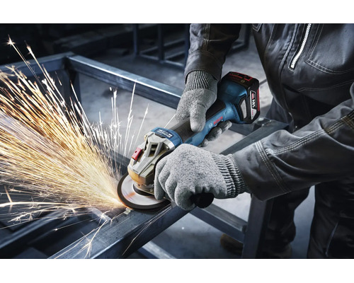 Vakman met werkhandschoenen gebruikt een Bosch accu haakse slijper voor het slijpen van een metalen frame met vonkenregen.