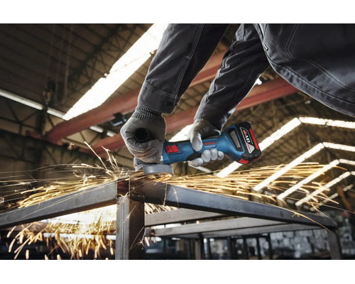 Een vakman in een werkplaats gebruikt een Bosch Professional accu haakse slijper voor het doorslijpen van metalen profielen met vonkvorming.