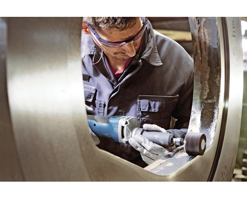 Een man gebruikt een schuurmachine op een stuk metaal.