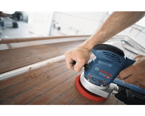 Een man schuurt een houten dek met een excentrische schuurmachine van Bosch