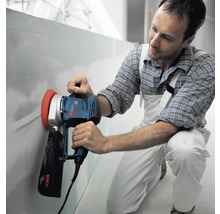 Man schuurt wand met een gipsplaats schuurmachine van Bosch