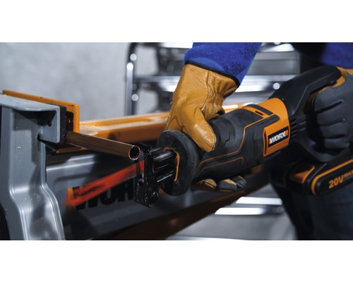 Een persoon zaagt een koperen buis door met een reciprozaag van Worx.