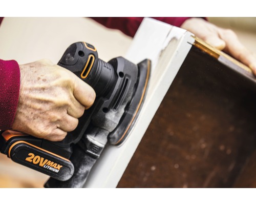 Een persoon gebruikt een excentrische schuurmachine om een stuk hout te schuren.