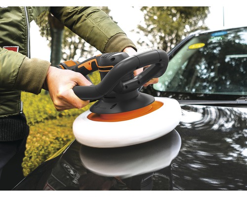 Een persoon polijst een auto met een polijstmachine.