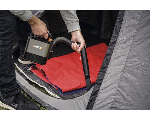 Een persoon gebruikt een draadloze WORX stofzuiger in een tent.