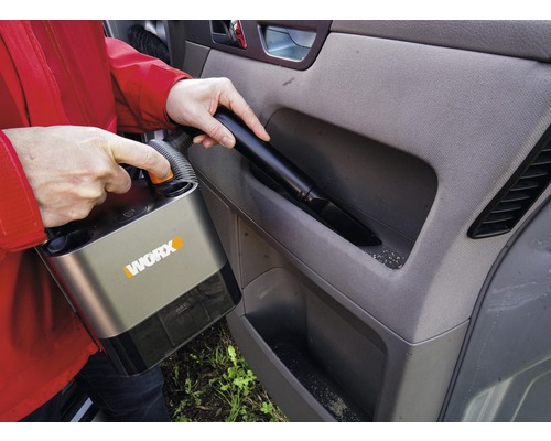 Persoon stofzuigt auto-interieur met snoerloze stofzuiger van het merk Worx