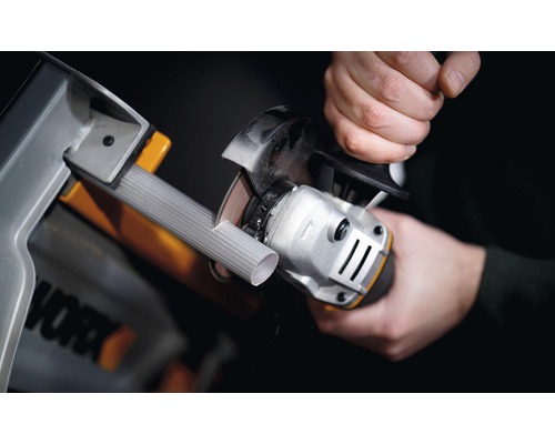 Iemand snijdt een buis met een haakse slijper in een werkplaats. Worx logo.