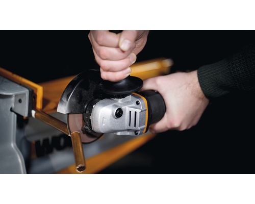 Close-up van een persoon die een metalen buis doorsnijdt met een haakse slijper.