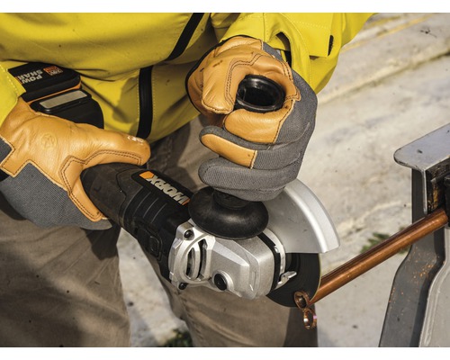 Een persoon snijdt een koperen buis met een handzaagmachine.