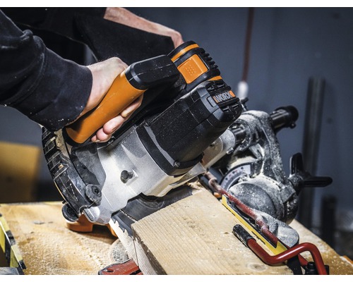 Een afkort- en verstekzaag zaagt een houten werkstuk. Worx Logo.