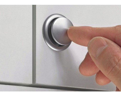 Een vinger drukt op een zilverkleurige meubelknop op een wit oppervlak