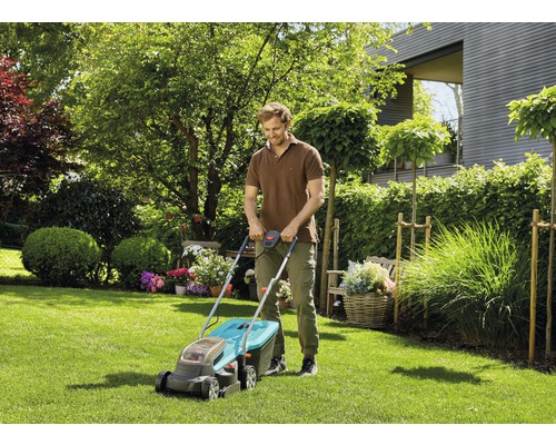 Een man maait het gazon in een tuin met een grasmaaier.