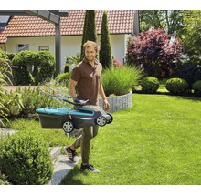 Man draagt een gazonmaaier door een tuin.