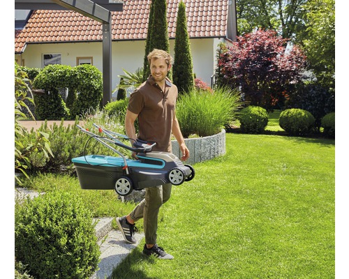 Man draagt een gazonmaaier door een tuin.