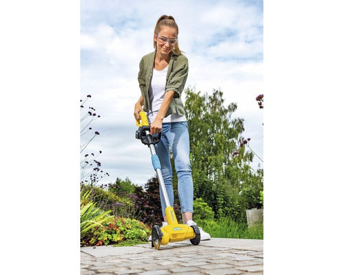 Een vrouw gebruikt een kantensnijder in de tuin.