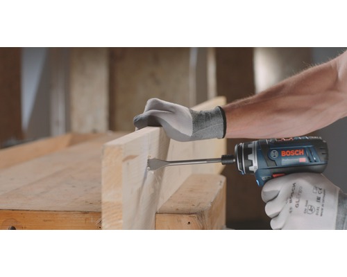 Iemand boort een gat in een houten plank met een accuboormachine.