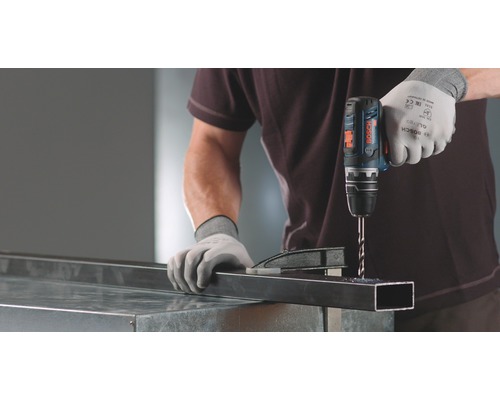 Ambachtsman boort een metalen profiel met een accuboormachine.