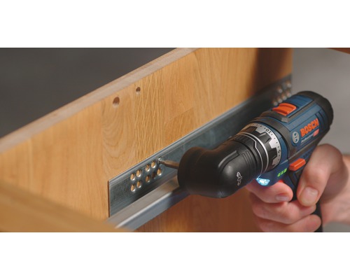 Boormachine die een ladegeleider aan een houten kast bevestigt