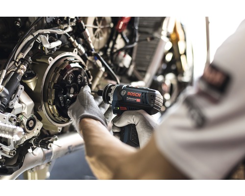 Een persoon gebruikt een Bosch accuschroevendraaier om een motorfiets te repareren.