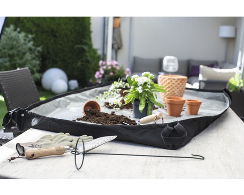 Tuinscène met plantaccessoires, plantenbak, potgrond en planten op een tafel