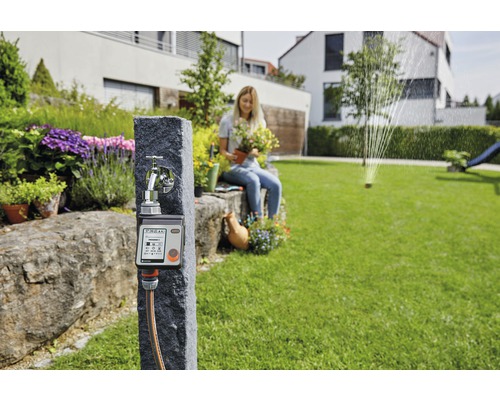 Gardena waterkraan met irrigatiebediening en vrouw met plant in de tuin